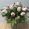 Pink roses arranged in a clear glass vase with greenery