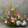 Large mixed floral arrangement with pink, yellow, blue, and green blooms