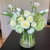 White roses and tulips arranged in a clear glass vase