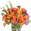 Orange and purple mixed flower arrangement in a glass vase