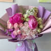 Bouquet of pink and white flowers wrapped in lavender paper