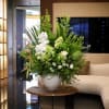 Large white and green floral arrangement in a round white vase