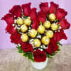 Heart-shaped bouquet of red roses with gold-wrapped chocolates in a white vase