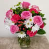 Pink roses and white daisies arranged in a glass vase