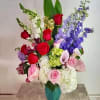Mixed bouquet of roses, calla lilies, hydrangeas, and delphinium in a teal vase