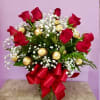 Red roses with white baby's breath in a glass vase with a red bow