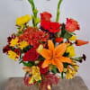Colorful mixed bouquet with roses, lilies, and daisies in a glass vase