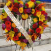 Large heart-shaped floral wreath on an easel with a memorial ribbon