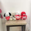 Four plush teddy bears holding heart pillows on a table