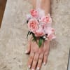 Pink rose wrist corsage with sheer ribbon on a person's wrist