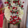 Standing floral tribute with red roses, white lilies, and white chrysanthemums