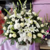 Large white floral arrangement with lilies, roses, and daisies in a basket