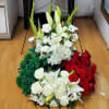 Three floral arrangements with white lilies, roses, and red roses on the floor