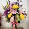 Mixed bouquet in a glass vase with pink roses, lilies, and yellow chrysanthemums