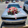 Large pink and white floral arrangement with ribbons on a silver car hood