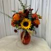 Bouquet of sunflowers, orange roses, and burgundy mums in a red vase