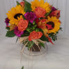 Bouquet of sunflowers, coral roses, and purple carnations in a low container