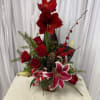 Red amaryllis and roses arranged with lilies in a vase