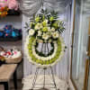 Large standing floral wreath with white and green flowers on an easel