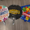 Three round congratulatory balloons lie on a floor.