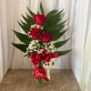 Red roses in a glass vase with a teddy bear and love ribbon