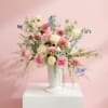 Pastel mixed flower arrangement in a white vase on a pedestal