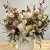 Large airy arrangement of white and pink flowers with burgundy accents in a tall white ceramic vase.