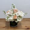 White and peach roses arranged in a black vase