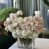 Blush and white roses arranged in a clear rectangular vase