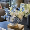 Blue and white floral arrangement in a white vase on a table
