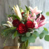 Bouquet of red roses and pink lilies in a clear glass vase