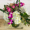 Pink roses and purple orchids arranged with white hydrangeas in a glass vase