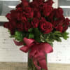 Bouquet of red roses in a glass vase with a burgundy ribbon