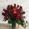 Red roses arranged in a clear glass vase with orange ribbon accents