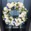 White and blue floral wreath on a stand