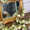 White rose garlands draped around an ornate gold mirror