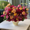 Mixed bouquet of pink, red, and peach roses in a gold vase