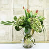 Bouquet of green hydrangeas and orange tulips in a glass vase