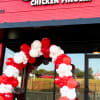 Red and white balloon arch outside a Guthrie's Chicken Fingers storefront
