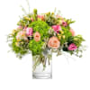 Bouquet of pink and peach roses with green hydrangeas in a clear glass vase