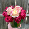 Short arrangement of cream and red roses in a clear glass vase held in one hand