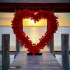 Heart-shaped red rose display on a dock at sunset
