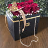 Red roses in a black gift box with a gold ribbon and chain handle