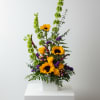 Tall floral arrangement with sunflowers and yellow roses in a white box vase