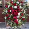 Large standing floral spray with red roses and white flowers on an easel
