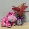 Pink plush hippo beside a potted red plant with a purple ribbon