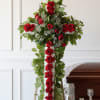 Red rose funeral cross arrangement on an easel beside a casket