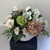 White and pale pink flowers arranged in a white pumpkin-shaped container