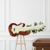 White and burgundy floral casket spray on an easel beside a wooden casket