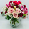 Mixed bouquet of pink lilies, roses, and carnations in a glass vase